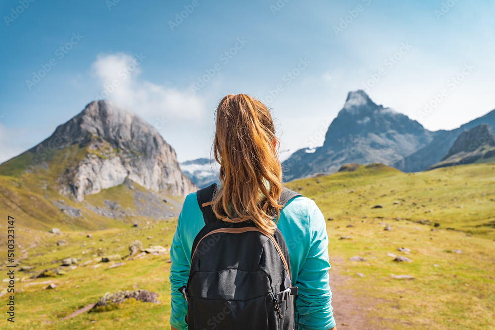 Young Attractive Woman With A Backpack hiking in a beautiful valley between mountains during the sunset. Discovery Travel Destination Concept Young Attractive Woman With A Backpack hiking in a beautiful valley between mountains during the sunset. Discovery Travel Destination Concept