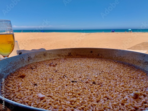 Arroz a banda, a typical valencian meal made with rice and seafood, similar to paella. The beach and the Mediterranean sea are on the background.