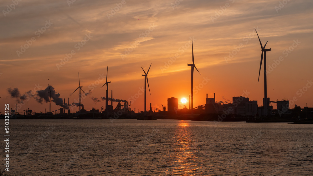 Silhouette of wind turbines in industrial area by the sea on sunset Silhouette of wind turbines in industrial area by the sea on sunset