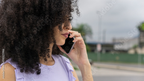 white curly brazilian woman empowered executive calling on cell phone 