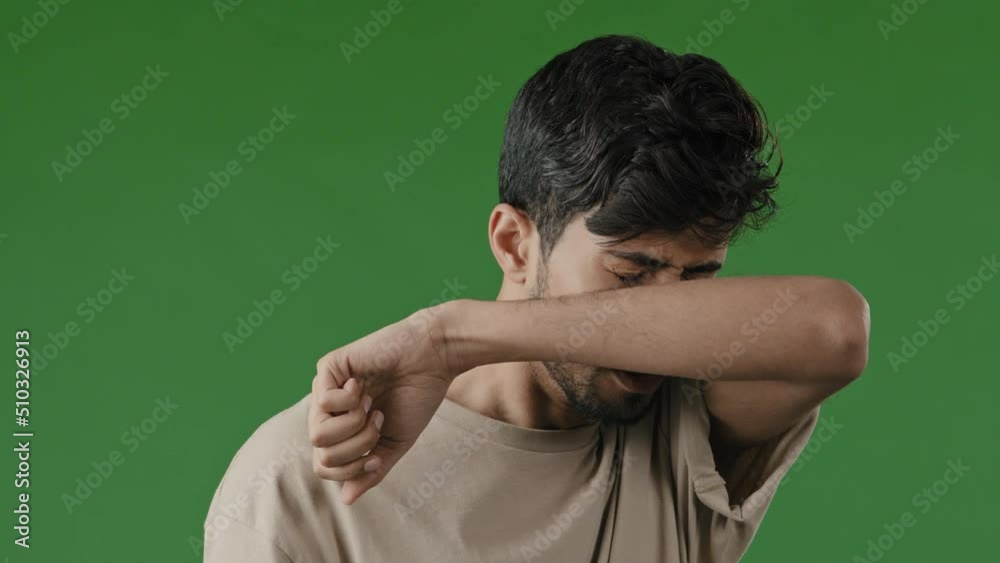 Sick allergic arab man indian male unwell guy sneeze cover face by hand prevent spread viral infection in green studio background has cold influenza symptoms suffer from respiratory allergy wipe nose Sick allergic arab man indian male unwell guy sneeze cover face by hand prevent spread viral infection in green studio background has cold influenza symptoms suffer from respiratory allergy wipe nose