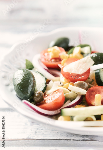 Simple Salad with Green Olives, Cucumber, Cherry Tomatoes and Capers. Bright wooden background. Close up.
