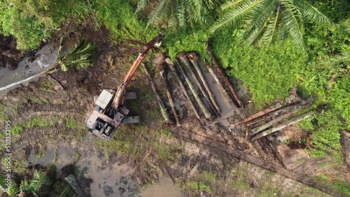 Aerial top down view excavator arrange the oil palm tree together during land clearing