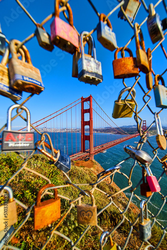 Locks covering chain linked fence with opening to sunset view of Golden Gate Bridge in San Francisco
