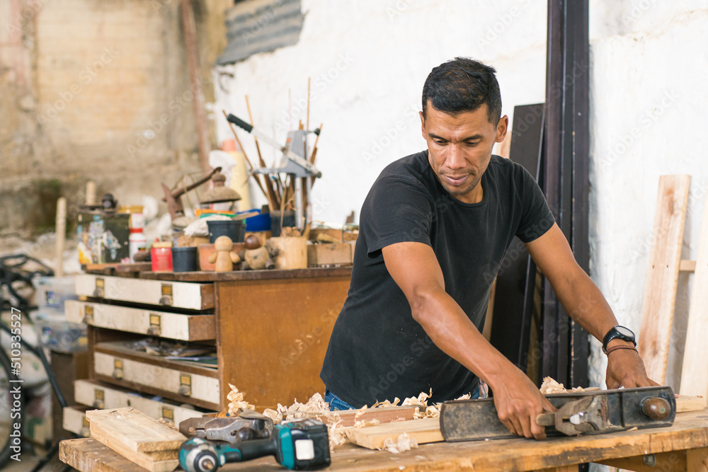 Work: Latin American worker in his workshop using different tools. Local carpentry of the town and its operator doing some work. Wood craftsman creating pieces and polishing wooden parts. Work: Latin American worker in his workshop using different tools. Local carpentry of the town and its operator doing some work. Wood craftsman creating pieces and polishing wooden parts.