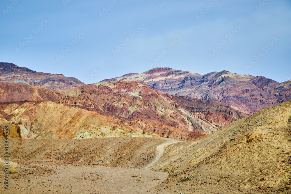 Path into Death Valley desert mountains with colorful patches