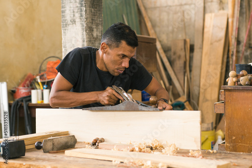 Work: Local carpentry of the town and its operator doing some work. Latin American worker in his workshop using different tools. Wood craftsman creating pieces and polishing wooden parts. 