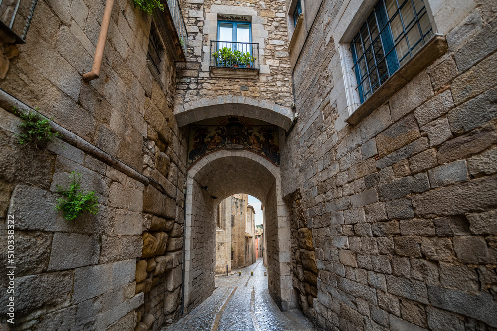 A small tunneled alley and back street of cobblestones in the medieval village of Girona Spain in the Catalonian district.