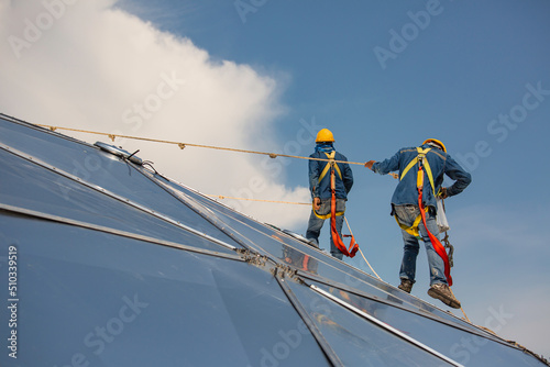 Male two workers rope access height safety connecting with eight knots safety harness, clipping into roof dome construction site oil tank.