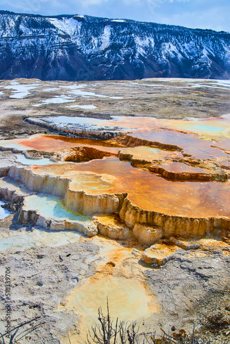 Stunning Mammoth Hot Spring terraces next to snow-covered mountains in Yellowstone photo