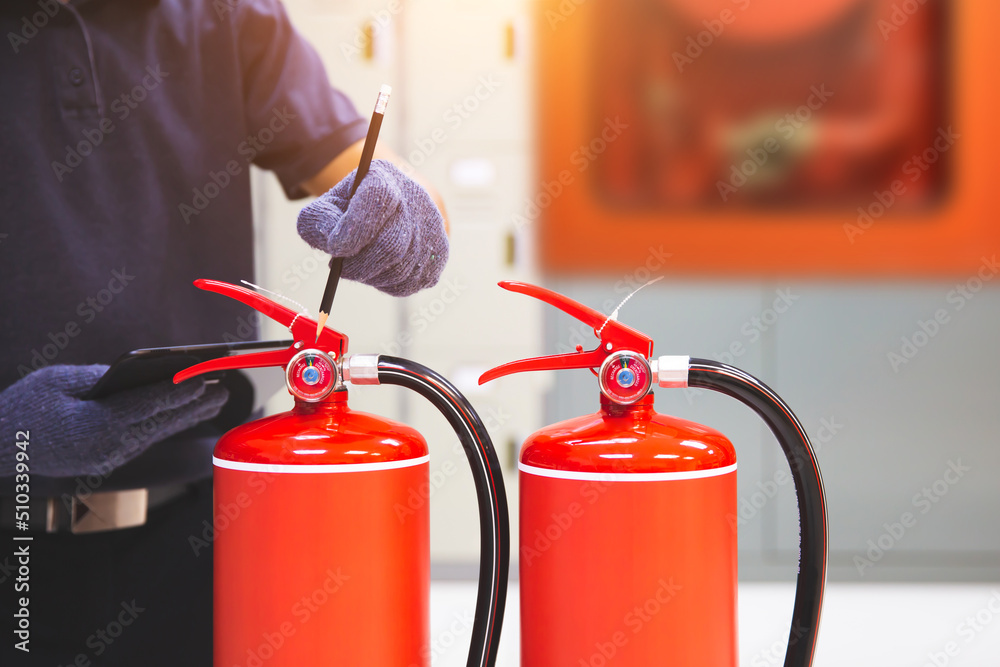 Obraz premium Fire extinguisher has hand engineer inspection checking pressure gauges to prepare fire equipment for protection and prevent emergency and safety rescue and alarm system training concept.