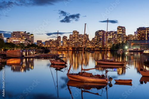 Urban city night, Vancouver twilight skyline. Boats on the False Creek. Buildings lights reflection on the river water. British Columbia, Canada.