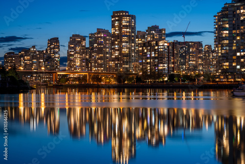 Urban city night, Vancouver twilight skyline. Buildings lights reflection on False Creek water. British Columbia, Canada.