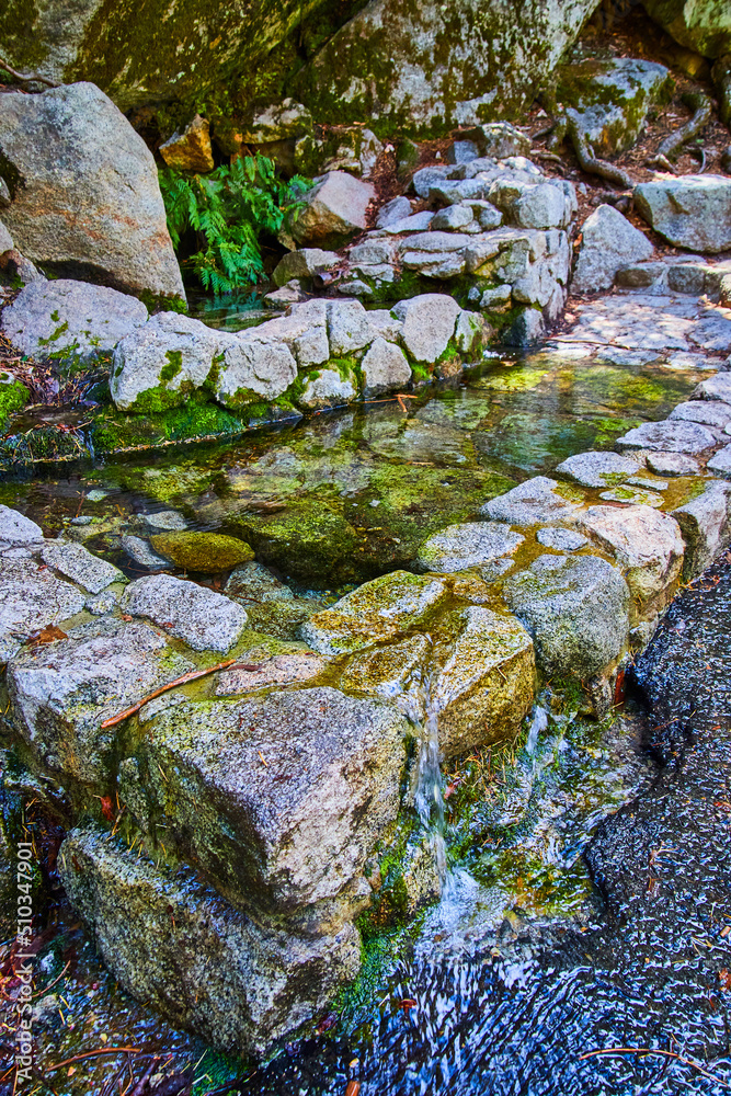 Manmade natural looking pool of water overflowing onto path Manmade natural looking pool of water overflowing onto path