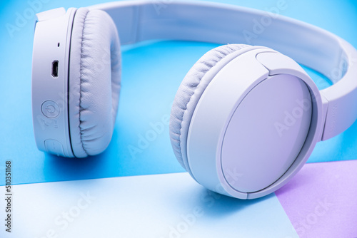 Close-up wireless headset isolated on a blue background. © Hamdi Bendali