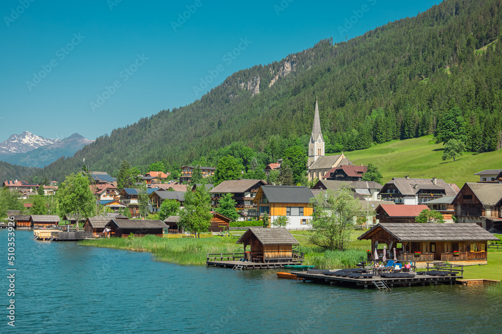Beautiful shores of weissensee lake in Austria, beautiful backdrop with alpine lake in the heat of the summer. Wide panorama taken from the bridge in the middle.