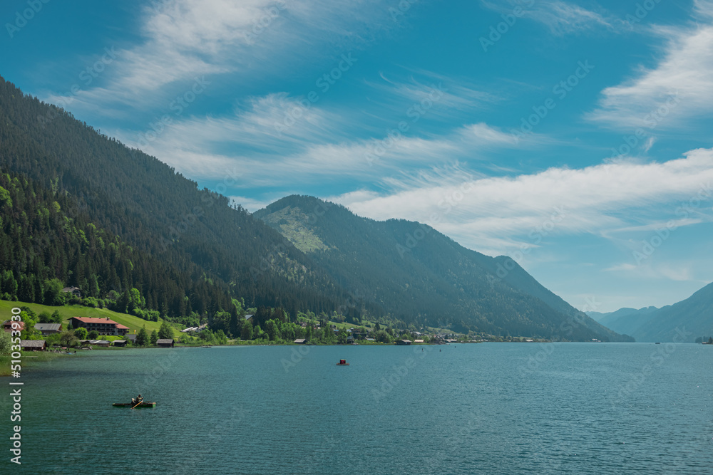 Beautiful shores of weissensee lake in Austria, beautiful backdrop with alpine lake in the heat of the summer. Wide panorama taken from the bridge in the middle.