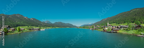 Beautiful shores of weissensee lake in Austria, beautiful backdrop with alpine lake in the heat of the summer. Wide panorama taken from the bridge in the middle.