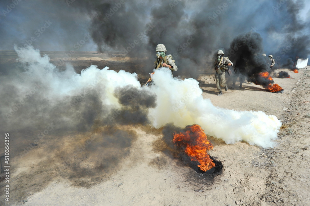 Obraz premium Almaty, Kazakhstan - 08.22.2012 : Soldiers pass a burning obstacle course in gas masks.
