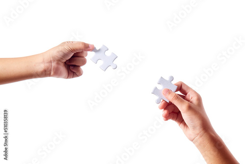 Close up hand two people holding jigsaws connecting puzzle elements on white isolated background