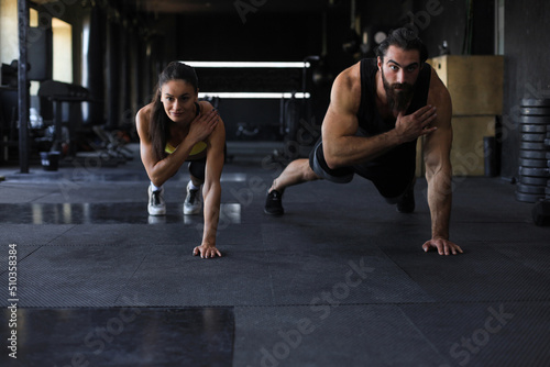 Portrait of beautiful young sports couple on a plank position.