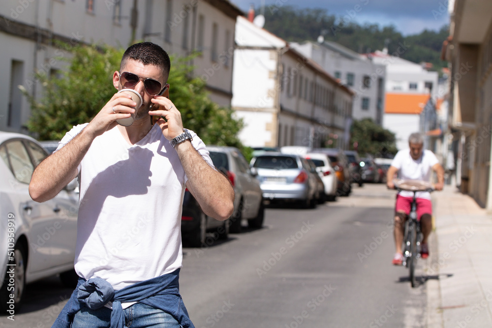 man with sunglasses on the street with phone and coffee to go man with sunglasses on the street with phone and coffee to go