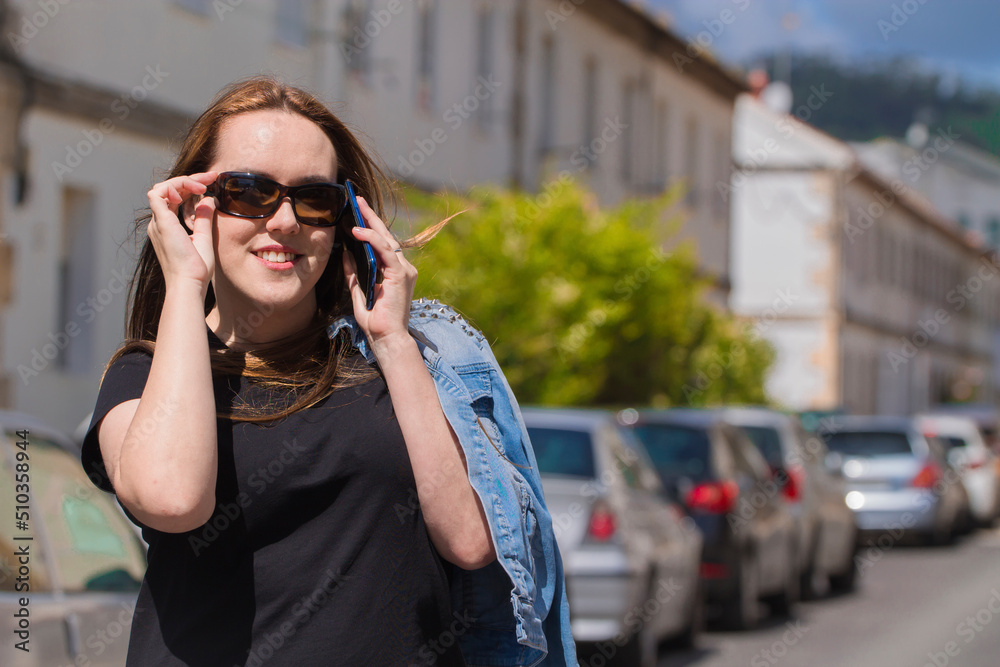 smiling woman with sunglasses and mobile phone on the street