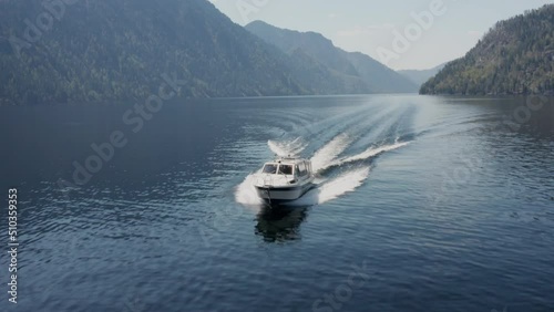 A pleasure boat goes along a picturesque lake on a sunny summer day
