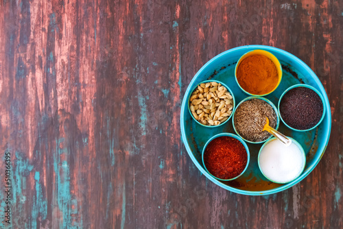 Fototapeta Naklejka Na Ścianę i Meble -  Spice box Indian masala dabba,indian spice box on wooden,Cardamom, turmeric, chilli powder, salt,mustard seeds,cumin,blur background