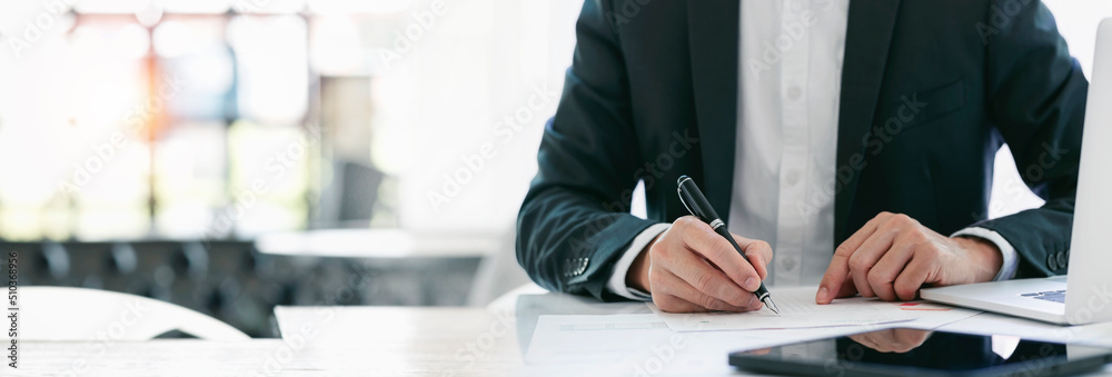 Cropped shot of businessman in suit writing business papers at desk in modern coworking office. copy space - obrazy, fototapety, plakaty 