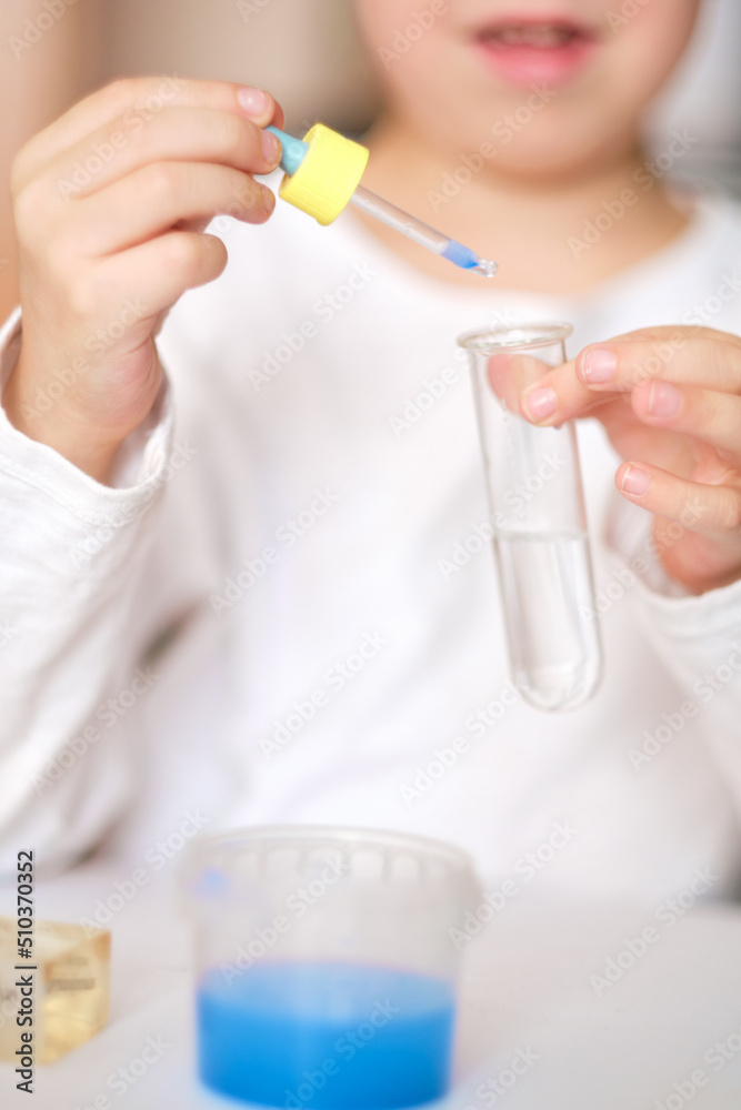 boy is engaged in scientific research. A child with a test tube and a pipette in his hands. The boy makes an experiment at home.