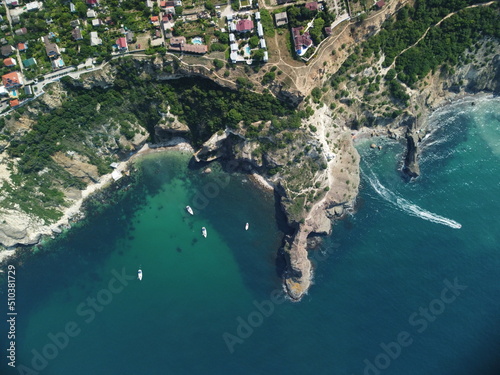 Aerial view from above on calm azure sea and volcanic rocky shores. Small waves on water surface in motion blur. Nature summer ocean sea beach background. Nobody. Holiday, vacation and travel concept © panophotograph