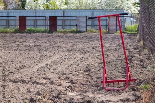 Red shovel in the form of a fork in the garden. Miracle shovel, handy tool. Manual cultivator. The cultivator is an effective tool for tillage. Bed loosening. Sustainable agricultural tools.