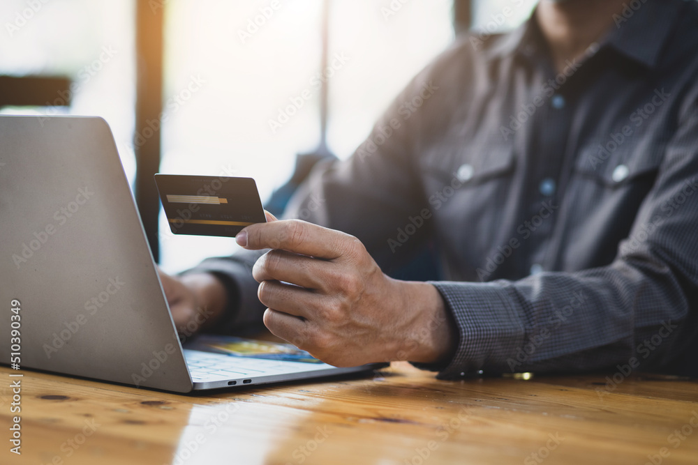 Man holding credit card using laptop. Online payment and shopping concept.