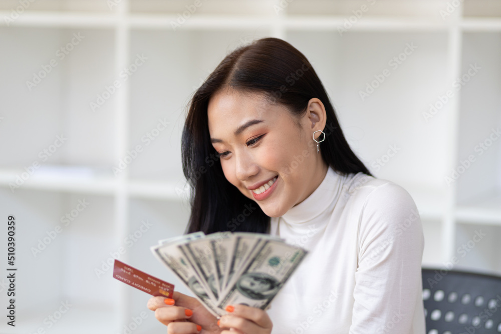 Cheerful happy Asian woman holding money and credit card. Cheerful happy Asian woman holding money and credit card.