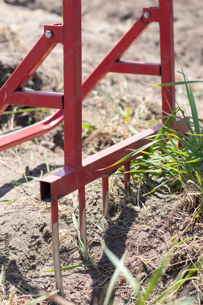 Red shovel in the form of a fork in the garden. Miracle shovel, handy tool. Manual cultivator. The cultivator is an effective tool for tillage. Bed loosening. Sustainable agricultural tools.