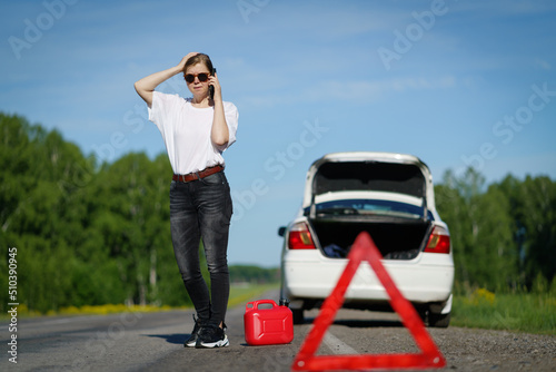Driver standing with empty fuel canister against car background. © PAstudio