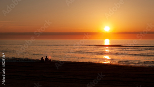 Couple watches the sunrise over the sea © Tamara  Harding