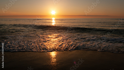 Sunrise over the ocean with gentle waves coming ashore