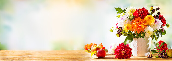 Autumn still life with garden flowers. Beautiful autumnal bouquet in vase, apples and berries on wooden table. Colorful dahlia and chrysanthemum.