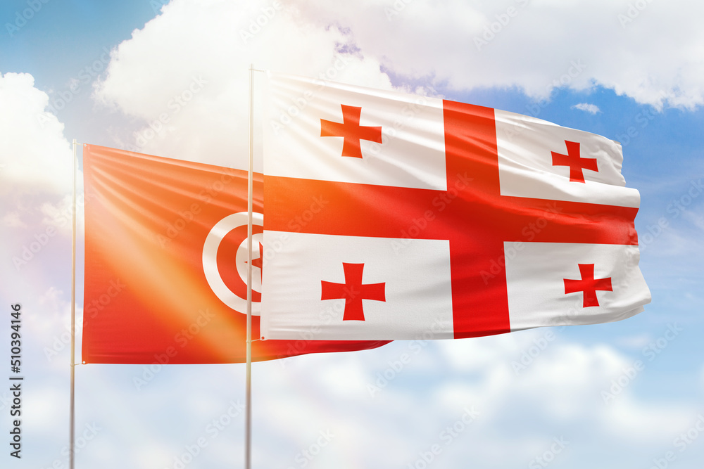 Sunny blue sky and flags of georgia and tunisia