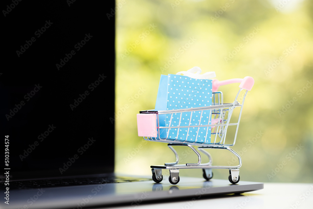 Paper boxes in a trolley and shopping bag on laptop computer