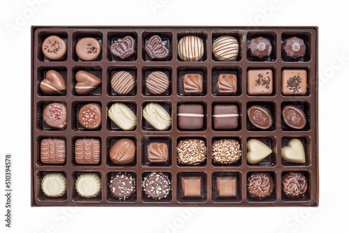 a set of festive chocolate sweets of various shapes and designs in a box isolated on a white background. view from above. top view © Evgenia