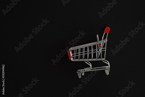 Mini red supermarket trolley on black background. Shopping concept