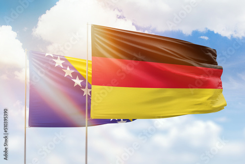 Sunny blue sky and flags of germany and bosnia