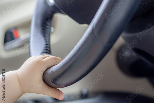 cute little baby playing in car,on driver seat,holding hand on steering wheel.toddler in teething period bites steering wheel.puts mouth.trip with kids,vacation,travel by car