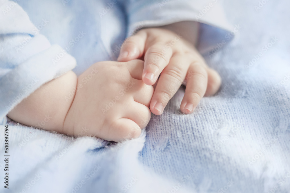 The baby's arms lie on a woolen warm blue blanket top view. Care for baby's delicate skin. Moisturizing and nourishing children's hands. Development of motor skills of hands The baby's arms lie on a woolen warm blue blanket top view. Care for baby's delicate skin. Moisturizing and nourishing children's hands. Development of motor skills of hands