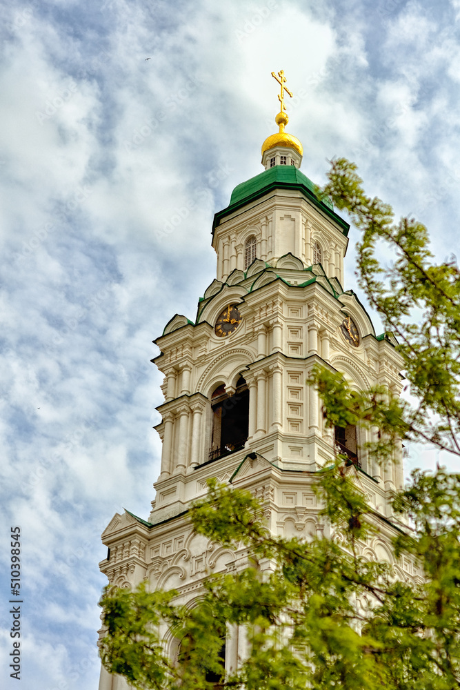 The ancient bell tower of the church on the background of a blue sky with clouds. 2