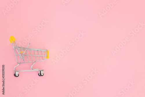 Small shopping cart on pink background