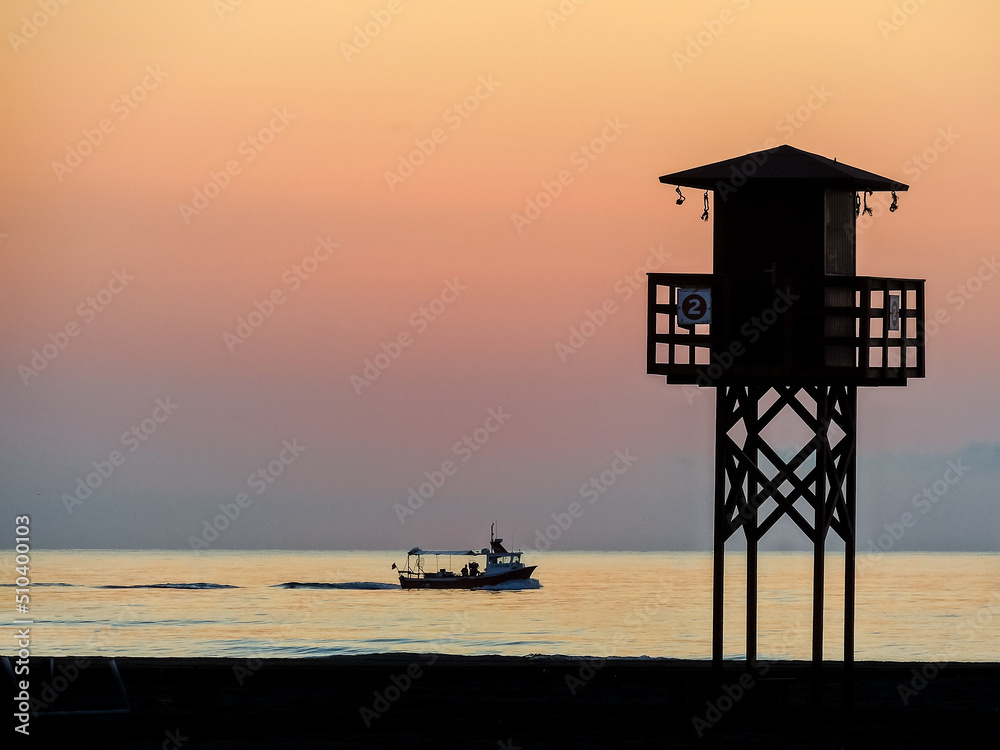 Red sunset on the beach with a lifeguard watchtower